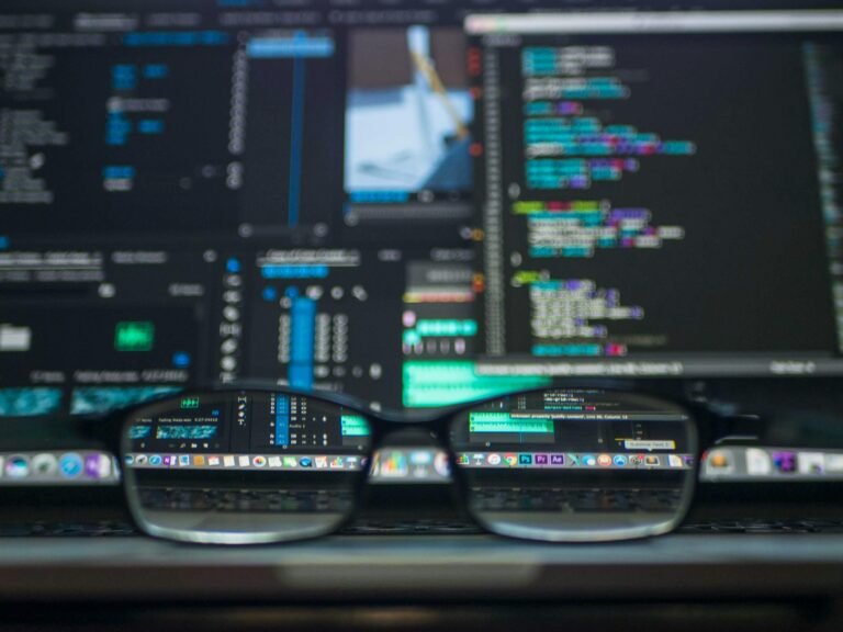 Glasses reflecting lines of code on a laptop screen, representing an IT freelancer at work