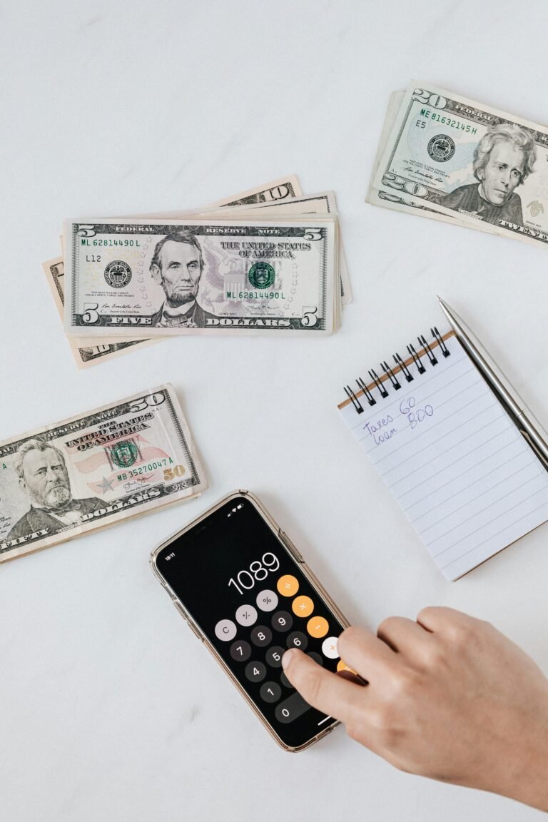 Cash, a phone calculator, and a handwritten note tracking taxes and a loan payment
